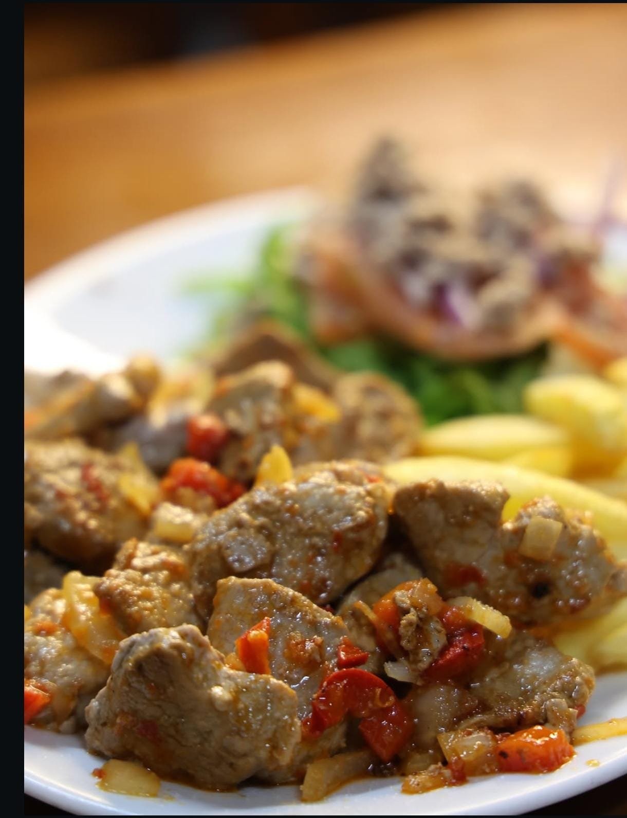 Plato de carne en trozos con pimiento, cebolla y papas